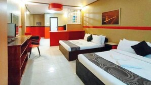 Een hotelkamer met twee bedden, een bureau en een rode accentmuur.