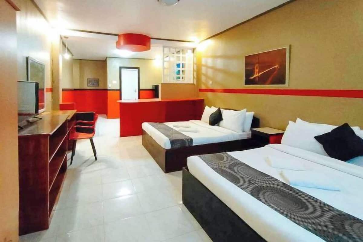 A hotel room with two beds, a desk, and a red accent wall.