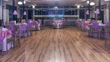 A banquet hall with round tables, purple tablecloths, and chairs.