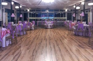 A banquet hall with round tables, purple tablecloths, and chairs.