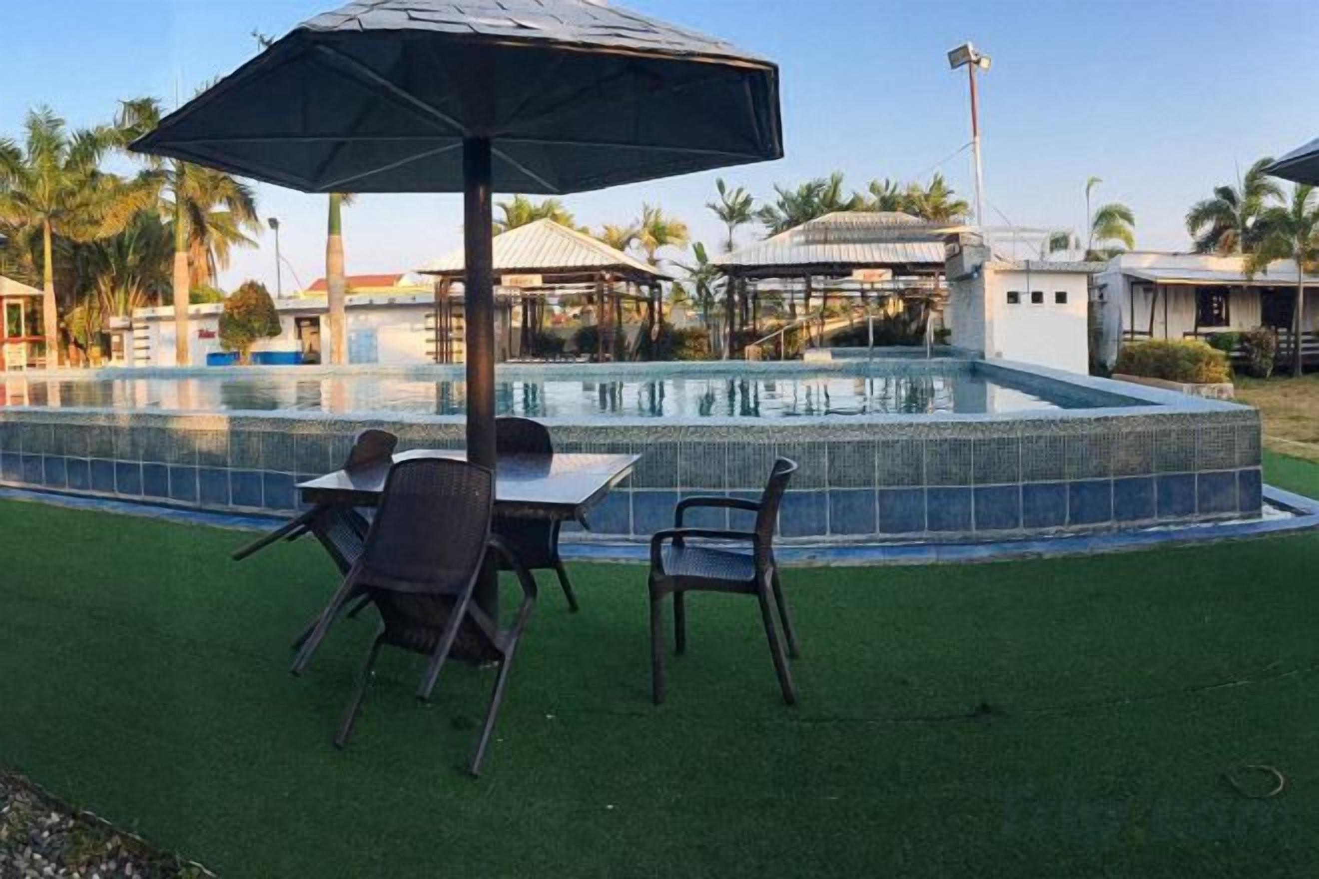 An outdoor pool area with a table and chairs, surrounded by artificial grass.