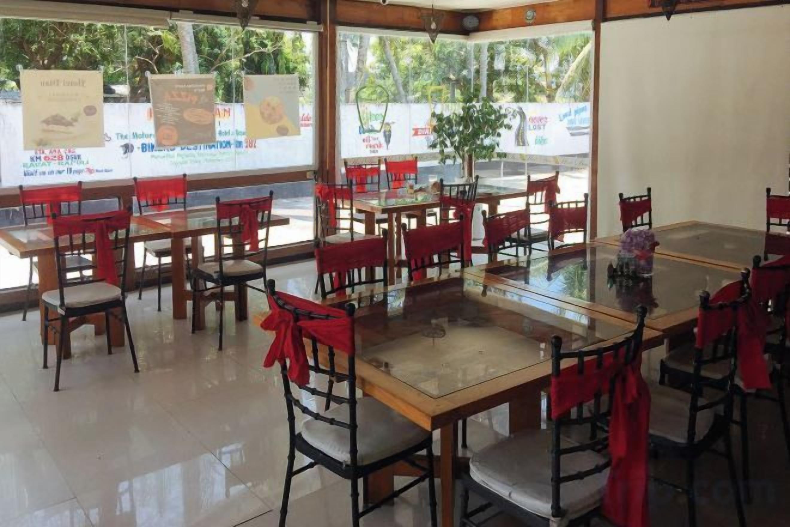 Ein Restaurant mit mehreren Tischen und Stühlen, einige davon mit roten Tischdecken.