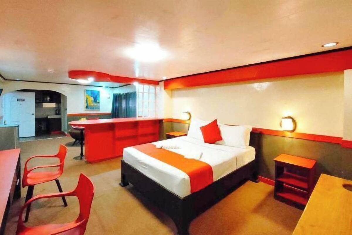 A hotel room with a bed, a desk, a chair, and a small table.