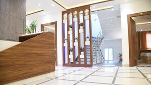 A reception area with a wooden desk, a staircase, and a view of the upper floor. - Cozy hotel in terrific Purnia with WiFi, AC (Purnia)