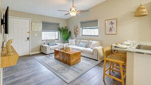 A living room with a wooden coffee table, a sofa, a TV, and a ceiling fan. - Dtwn Palm Harbor Condo: Walk to Water! (Palm Harbor)