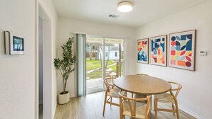 A dining area with a round table and four chairs, a potted plant, and a sliding glass door leading to a patio.