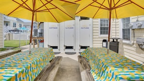 A poolside area with two wooden benches, yellow umbrellas, and a pool table. - < 1/2 Mi to Boardwalk: Roomy Wildwood Retreat! (North Wildwood)
