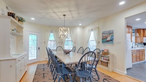 A dining room with a large table, chairs, and a chandelier. There is a kitchen area visible in the background. - < 1/2 Mi to Boardwalk: Roomy Wildwood Retreat! (North Wildwood)