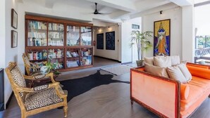 A spacious living room with a large bookshelf, a sofa, and a decorative wall piece. - Maison De Chiangrai (Chiang Rai)