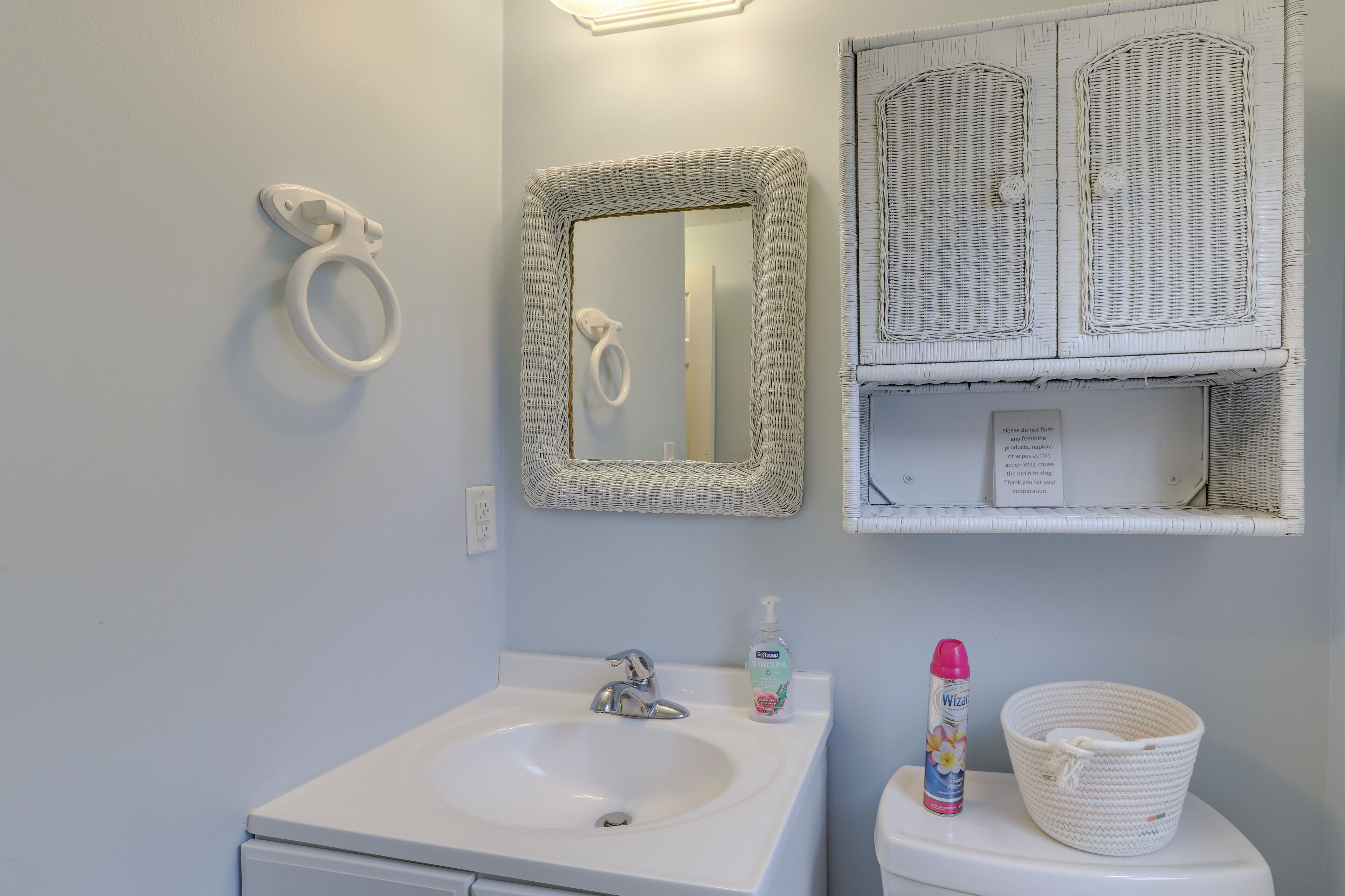A bathroom with a white sink, a mirror, and wicker baskets on the wall.