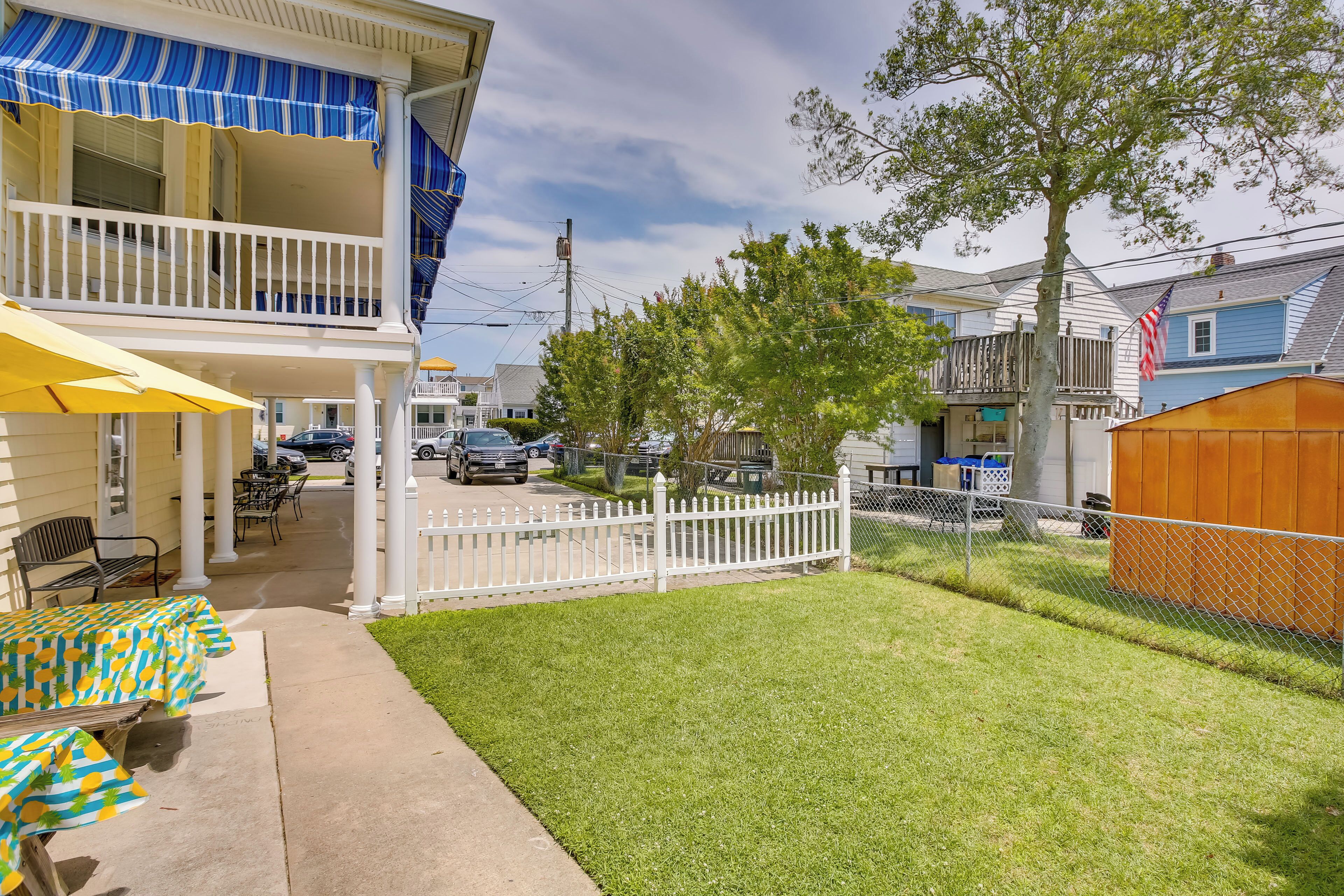 A two-story building with a balcony, a covered patio with tables, and a fenced yard.