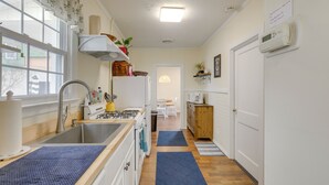 A kitchen with a stove, sink, and a microwave. There is a window with curtains, a door, and a thermostat on the wall. - Walk to Beach & Boardwalk: Jersey Shore Cottage! (North Wildwood)