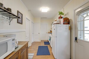 Una cocina estrecha con electrodomésticos blancos, armarios de madera y una ventana.