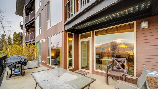 A modern building with large windows, outdoor seating, and a covered table. - Walk to Lake Chelan: Condo w/ Pool Access (Chelan)