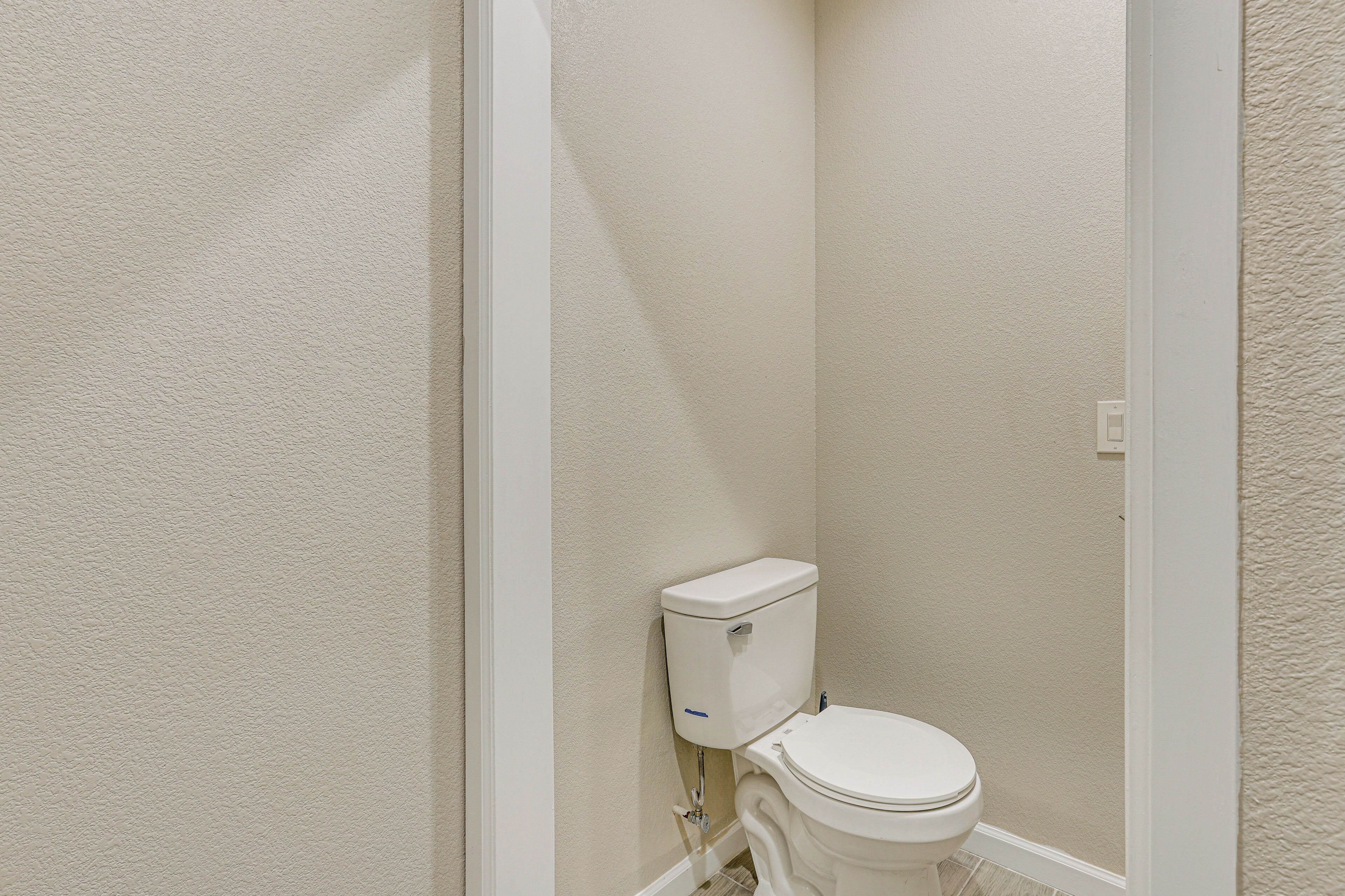 A small, white bathroom with a toilet, a wall-mounted tank, and a tiled floor.