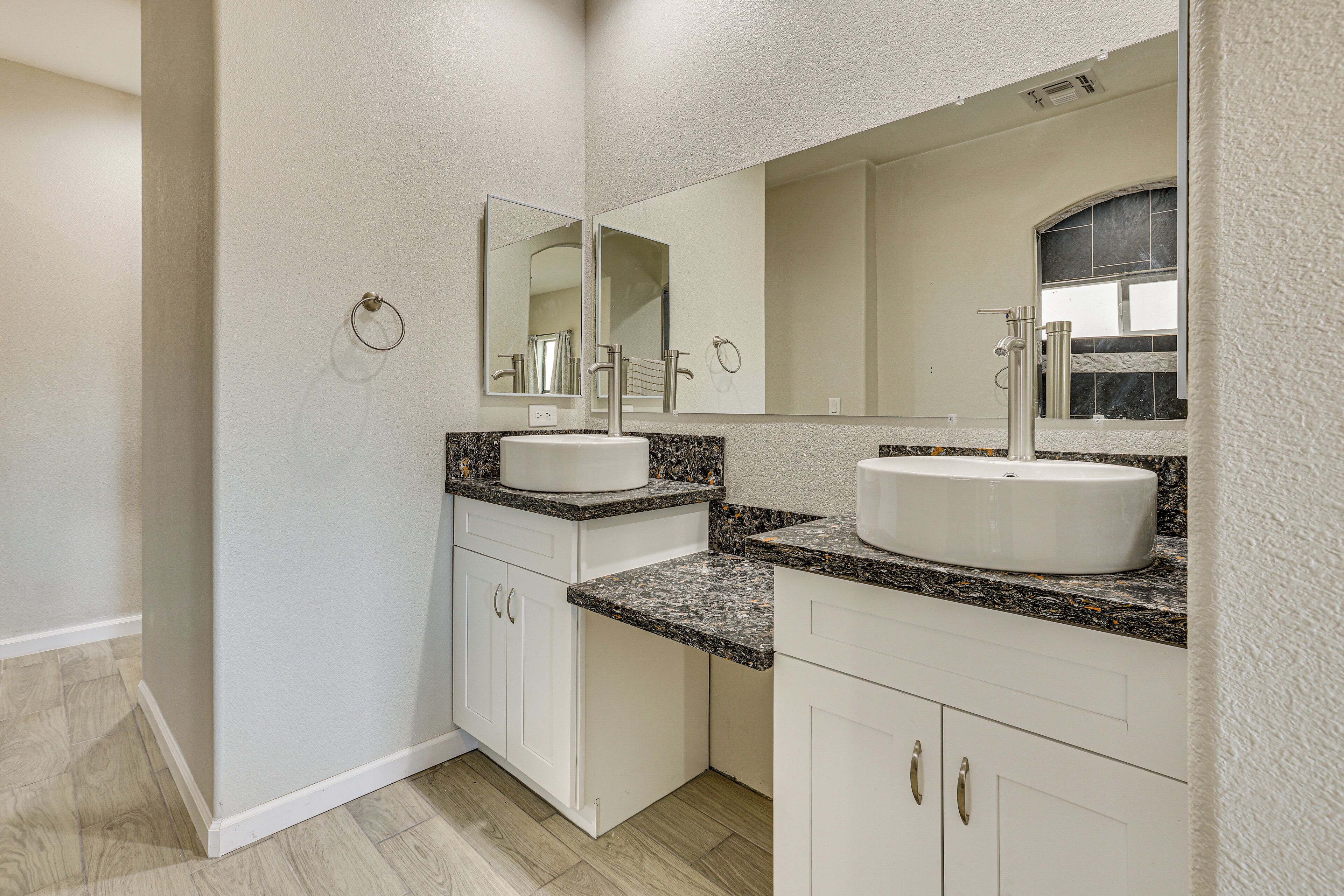 A bathroom with two sinks, white cabinetry, granite countertops, and a large mirror.