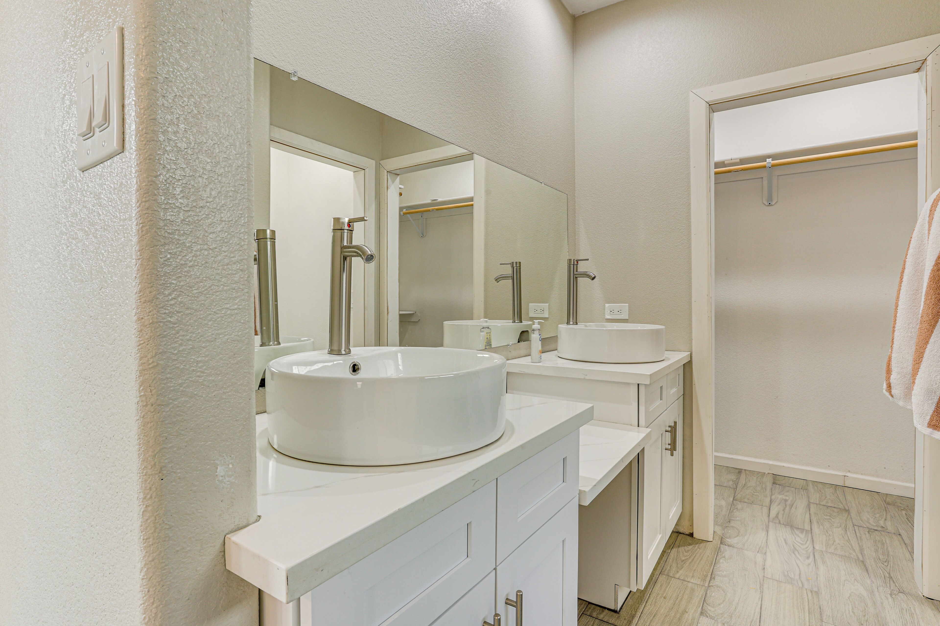 Une salle de bain moderne avec deux lavabos, un grand miroir et un dressing.