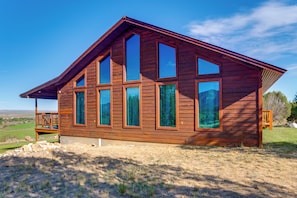 A wooden cabin with multiple large windows, a deck, and a clear view of the surrounding landscape. - Mtn-view Escape w/ Office Space in Cortez! (Cortez)