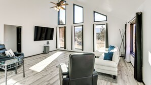 A spacious living room with a large TV, leather chairs, and a ceiling fan.