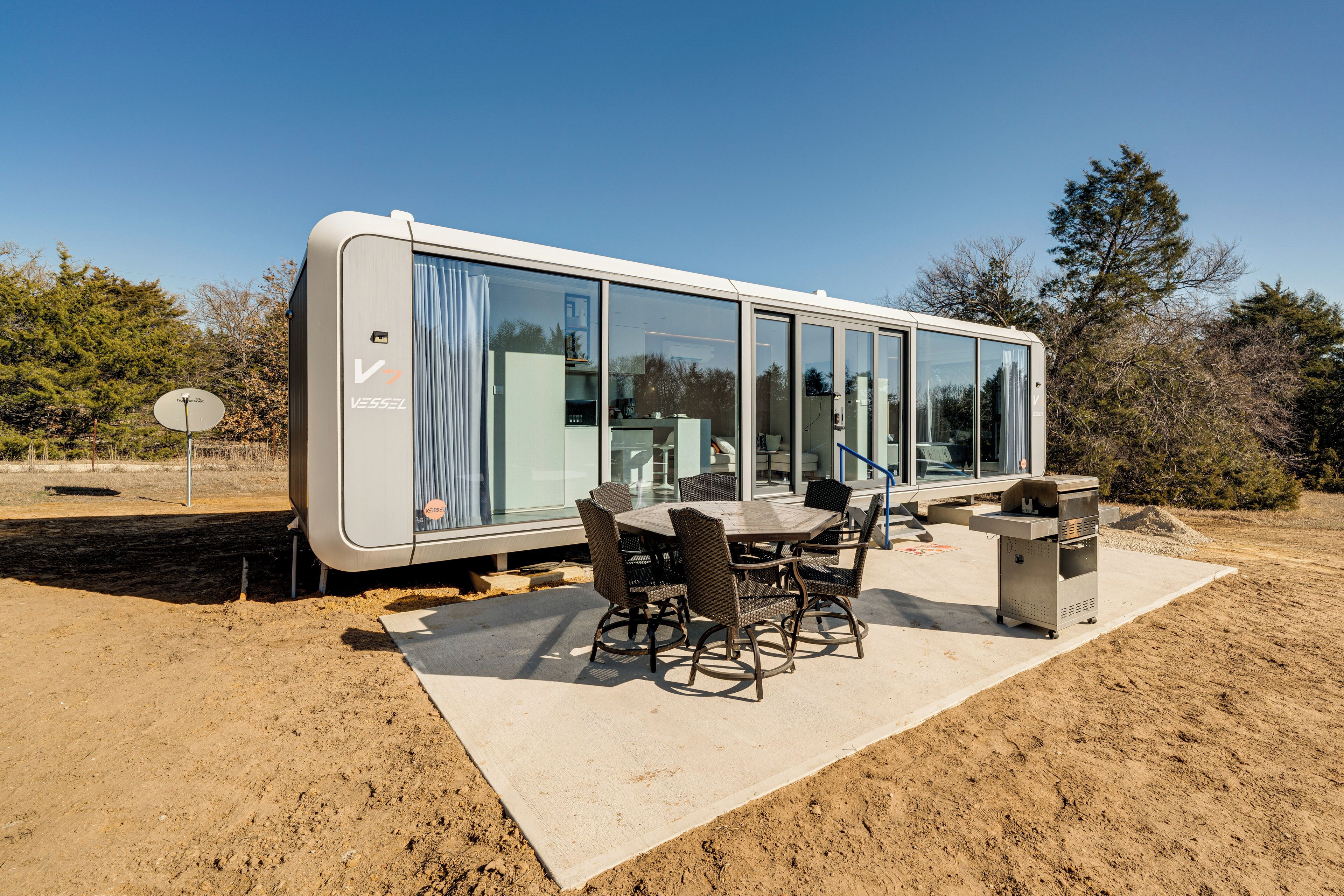 A modern RV with a dining area, including a table and chairs, and a small kitchenette.