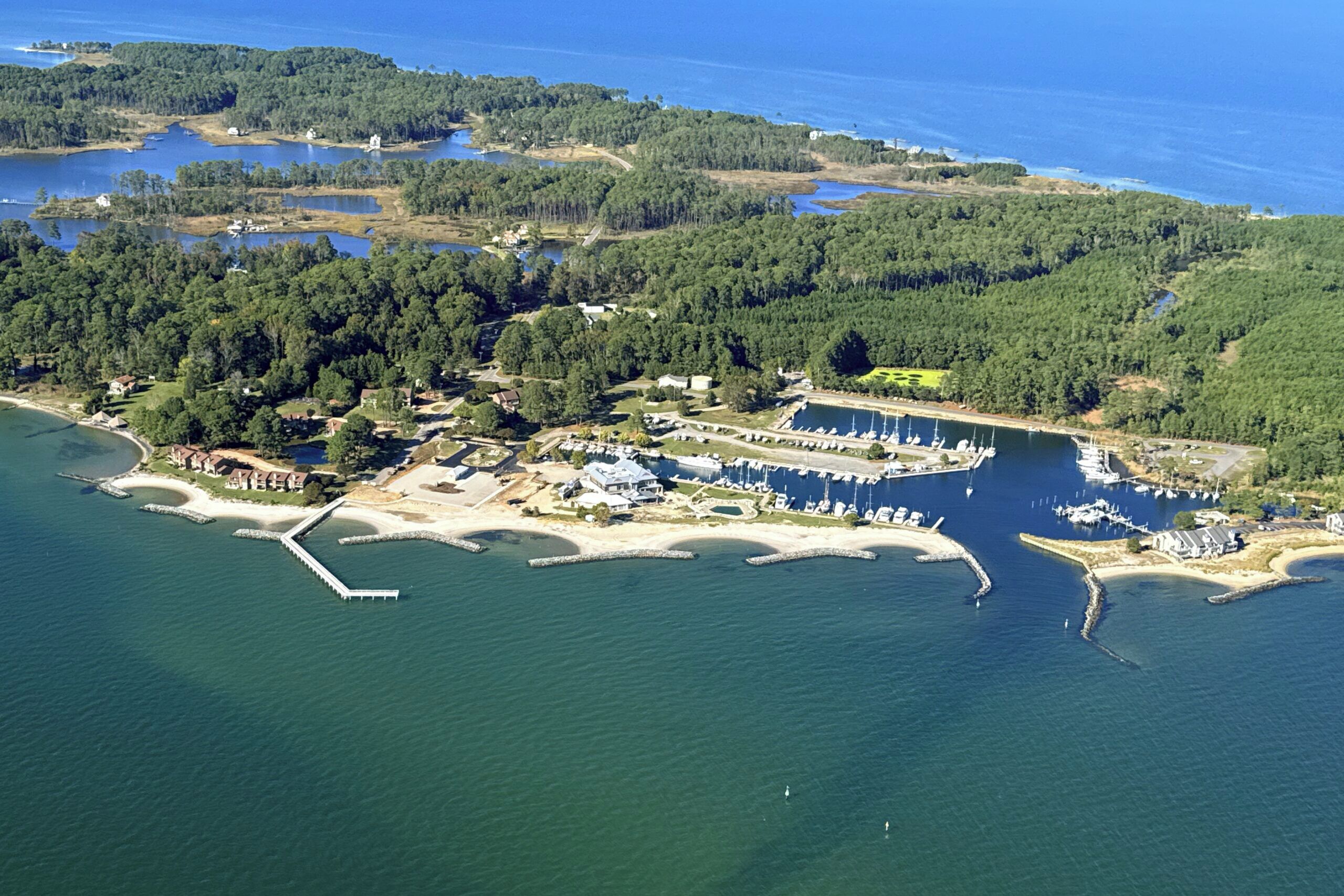 An aerial view of a coastal area with a marina, boats, and residential buildings.