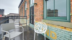 A balcony with wicker chairs and a white chair, a brick building with green window frames, and a yellow painted wall. - < 1 Mi to Wittenberg: Eclectic Loft w/ Parking! (Springfield)