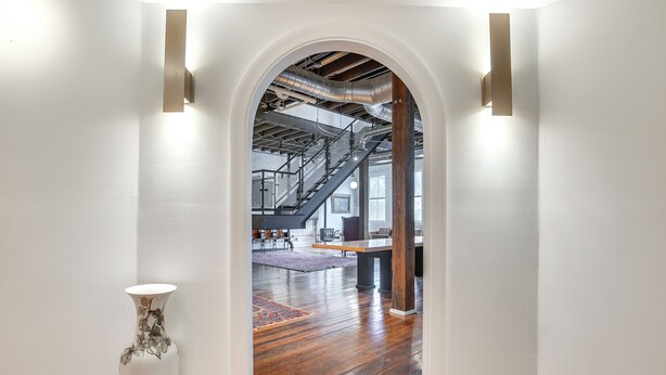 An arched doorway leading to a room with wooden flooring, a staircase, and a modern industrial ceiling. - < 1 Mi to Wittenberg: Eclectic Loft w/ Parking! (Springfield)