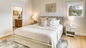 A bedroom with a large bed, bedside tables, a nightstand, a wardrobe, and a window with a view of trees. - Private Hot Tub & Patio: Spacious Cle Elum Home (Cle Elum)