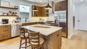 A modern kitchen with wooden cabinets, stainless steel appliances, and a central island with bar stools. - Private Hot Tub & Patio: Spacious Cle Elum Home (Cle Elum)
