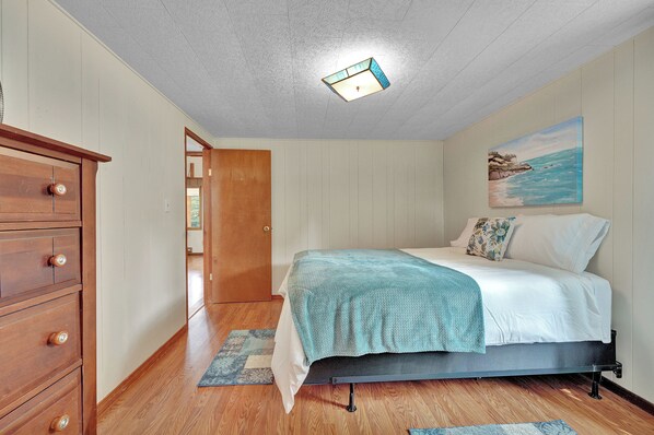A bedroom with a bed, wooden dresser, and a painting on the wall. - Private Dock & Lake Views: Home on Lime Lake (Machias)