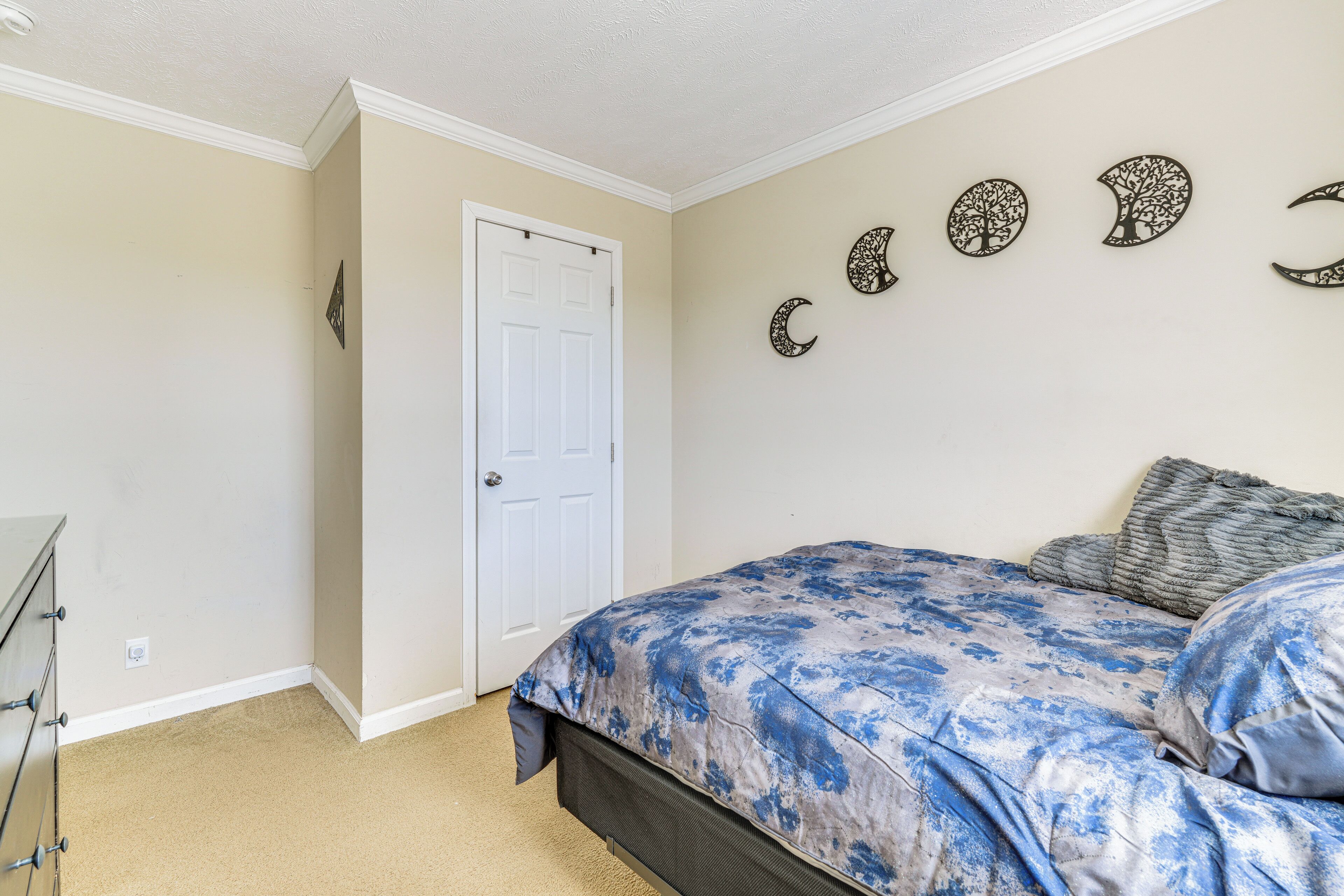 Une chambre à coucher avec un lit, une commode, une porte et des éléments décoratifs sur les murs.