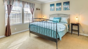 A bedroom with a metal bed frame, a bedside table, and a window with curtains. - Mountain View Retreat Relax & Unwind (Midway)
