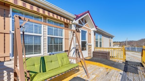 A wooden deck with a green cushioned sofa, a wooden swing, and a wooden ladder leading to a deck door. - Mountain View Retreat Relax & Unwind (Midway)