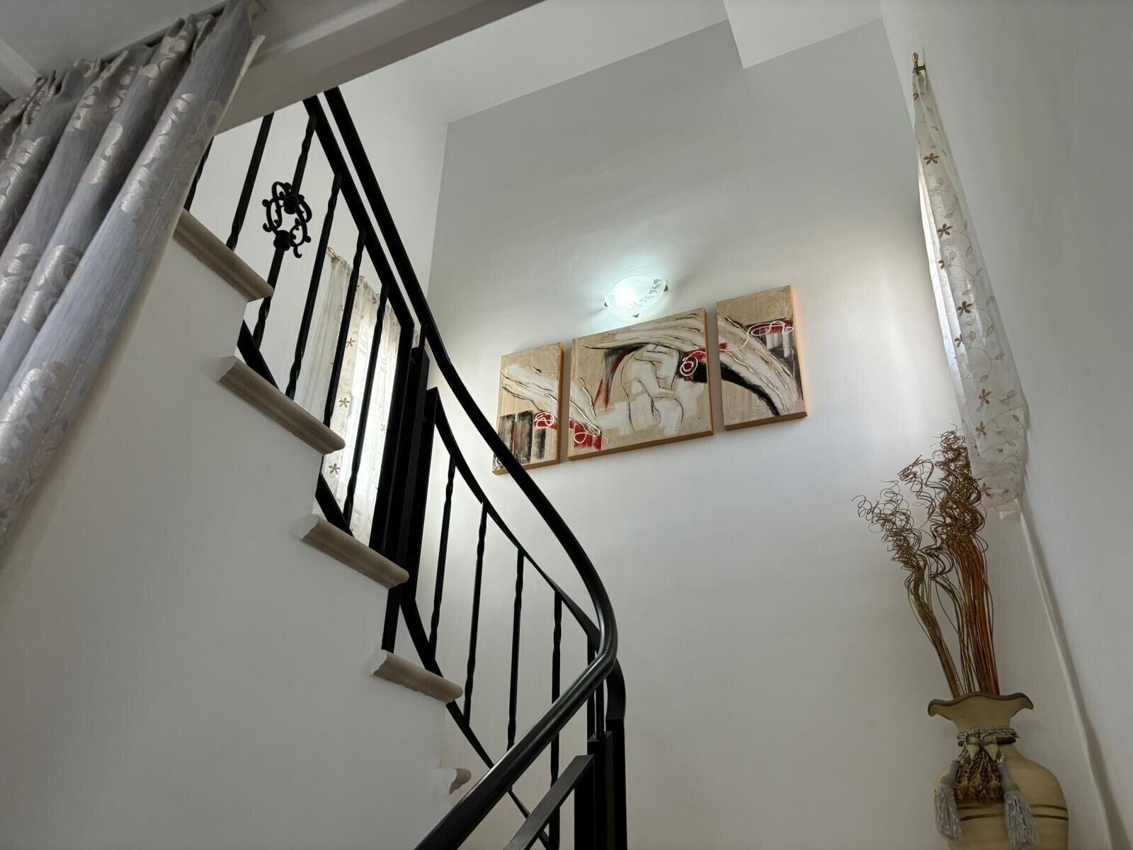 Eine Treppe mit schwarzen Geländern, einem Wandbild und einer dekorativen Vase.