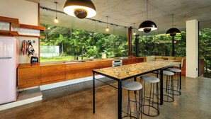 Una cocina moderna con encimera de madera, taburetes de bar e iluminación colgante.