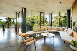 A modern living room with a curved sofa, a round coffee table, and a wicker chair.