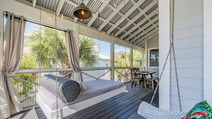 Un espace extérieur aménagé, abrité et doté d’un lit-balancelle, d’une table à manger et de chaises.