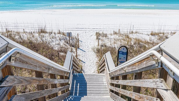 Un escalier en bois mène à une plage d’où l’on a une vue dégagée sur l’océan.