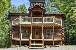 A log cabin with a central entrance, a second-floor balcony, and a third-floor balcony with a wooden roof. - Private Indoor Pool, Hot Tub, Fire Pit, Pool Table, Free Attractions! (Cosby)