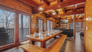 A wooden cabin interior with a long dining table set for four, benches, and a fireplace. - Private Indoor Pool, Hot Tub, Fire Pit, Pool Table, Free Attractions! (Cosby)