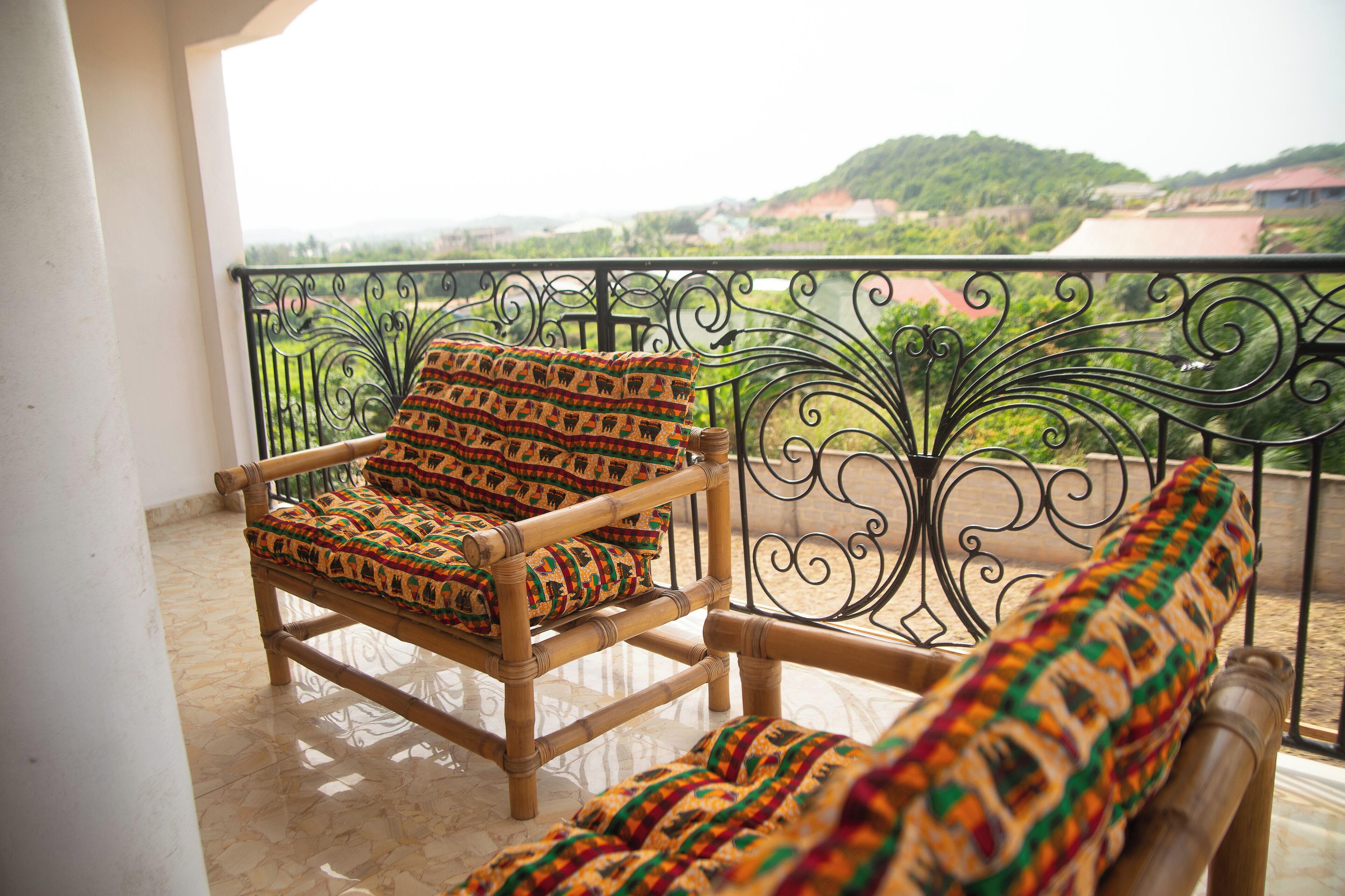 A wooden chair with a patterned cushion on a balcony with a metal railing.