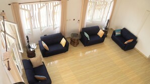 A spacious living room with two sofas, a coffee table, and a wooden side table. - Pito Guest House (Elmina)