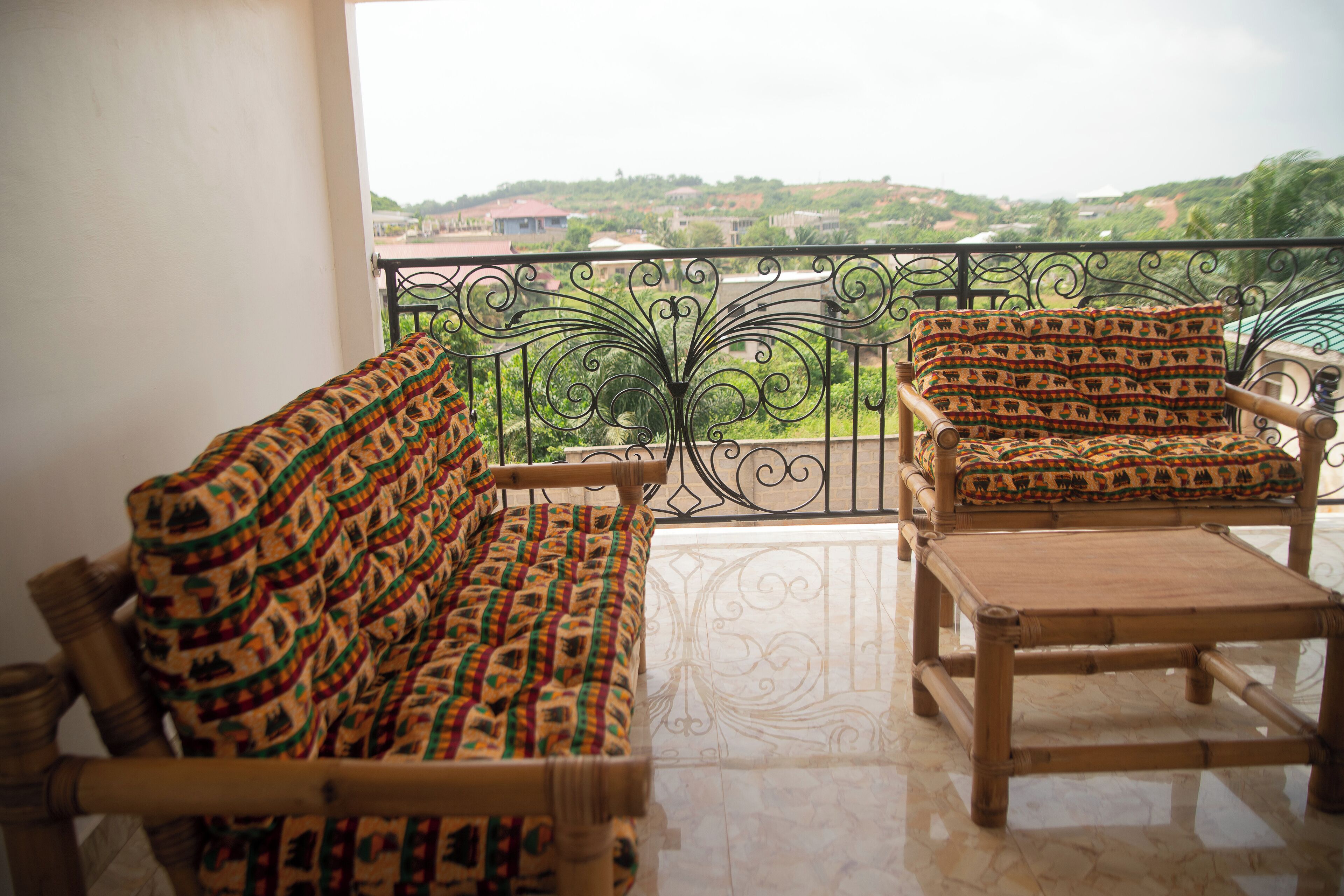 A balcony with a sofa and armchair, a small table, and a decorative metal railing.