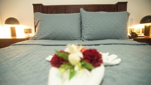A neatly made bed with a blue quilt and a floral arrangement in the center. - Pito Guest House (Elmina)