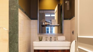 A bathroom with a marble floor, wooden vanity, white sink, and a mirror above the sink. - Palais Bourbon Hotel - Room 12- 2P - Invalides (Paris)