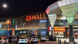 Een modern gebouw met een opvallend 'iOiMALL KUALA' bord, een restaurant genaamd 'GUOMA EXPRESS', en verschillende geparkeerde auto's ervoor.