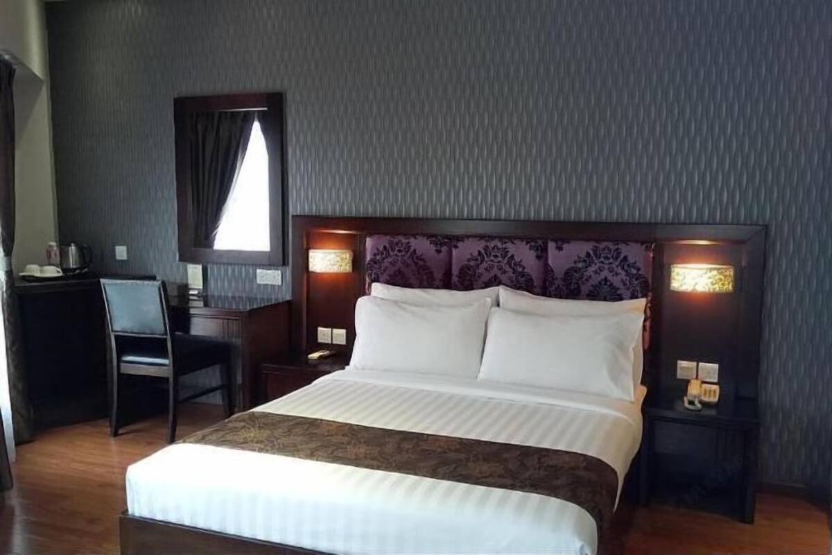 Habitación de hotel con cama, escritorio, silla y dos lámparas de noche.