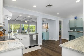 A modern kitchen with white cabinetry, a stainless steel dishwasher, and a marble countertop.