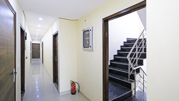 Un pasillo con extintor, letrero de advertencia y escalera.