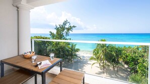 A balcony with a wooden table, a bowl, and a glass of water. - Seabreeze 8 - Luxury 4-bedroom on Seven Mile Beach (Seven Mile Beach)